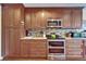 Kitchen featuring custom wood cabinets, granite countertops, mosaic backsplash, and stainless steel appliances at 1710 New Bedford Dr, Sun City Center, FL 33573