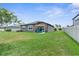 Spacious backyard with lush green lawn and a cozy patio featuring a shade umbrella and Adirondack chairs at 18414 Malinche Loop, Spring Hill, FL 34610