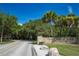 Scenic entrance to Fred Howard Park with stone signage, lush trees, and paved road under a bright blue sky at 2005 N Pointe Alexis Dr, Tarpon Springs, FL 34689