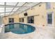 Bright indoor pool area featuring a sleek pool, light tile flooring, and large sliding glass doors at 2005 N Pointe Alexis Dr, Tarpon Springs, FL 34689