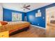 Vibrant bedroom with blue walls, hardwood floors, a ceiling fan, and an attached room at 217 2Nd Sw St, Largo, FL 33770