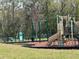 Community playground featuring swings, slides, and a playground area surrounded by woods at 3032 Inlet Breeze Way, Holiday, FL 34691