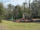 Community playground featuring swings, slides, and a playground area surrounded by woods at 3032 Inlet Breeze Way, Holiday, FL 34691