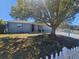 A lovely home exterior with a mature tree, white picket fence, and well-maintained lawn at 3136 Primrose Dr, Holiday, FL 34691