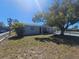 Exterior daytime view featuring a mature shade tree, tidy lawn, and charming white picket fence at 3136 Primrose Dr, Holiday, FL 34691