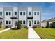 Modern townhome exterior shows neutral paint and well-maintained landscaping, including green grass and healthy plants at 3402 E 28Th Ave # 7, Tampa, FL 33605