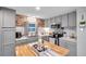 Modern kitchen with stainless steel appliances, light gray cabinetry, and wood block island at 3834 Kim Dr, Wesley Chapel, FL 33543