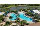 Aerial view of a community pool with palm trees and lounge chairs surrounded by lush greenery near a peaceful lake at 5420 Cicerone St # 103, Sarasota, FL 34238