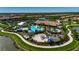 Aerial view of a community pool area featuring multiple pools, splash pad, playground and lounge areas, surrounded by lush landscaping at 5420 Cicerone St # 103, Sarasota, FL 34238