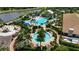 Aerial view of a luxurious community pool area with palm trees, sun loungers, private cabanas, and lush landscaping at 5420 Cicerone St # 103, Sarasota, FL 34238