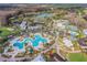 Scenic aerial view of a community with a large pool, tennis courts, golf course and beautiful landscaping at 5473 Blue Heron Ln, Wesley Chapel, FL 33543