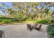Beautiful backyard with mature trees, green lawn, landscaped garden beds and stone patio seating at 5473 Blue Heron Ln, Wesley Chapel, FL 33543