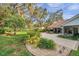 Landscaped backyard with a tile roof home, mature trees, and outdoor seating area at 5473 Blue Heron Ln, Wesley Chapel, FL 33543