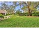 A backyard featuring manicured lawn, mature hedges, and a charming patio area at 5473 Blue Heron Ln, Wesley Chapel, FL 33543