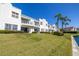 Condominium exterior featuring a grassy lawn, tropical plants, and building balconies at 6061 Bahia Del Mar Blvd # 112, St Petersburg, FL 33715