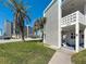 The exterior of a building next to a lush lawn and palm trees are captured on a clear day at 7050 Sunset Way # 26, St Pete Beach, FL 33706