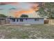 Back of house at sunset, fenced-in yard with some grass and a small brick patio at 7314 Princeton Dr, Hudson, FL 34667
