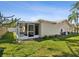 Backyard with a screen porch, green grass, garden beds along the exterior of the home and palm tree at 803 Helmsman Way, Palm Harbor, FL 34685