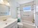 Bright bathroom with a white vanity, a shower-tub combo, and a window providing natural light at 803 Helmsman Way, Palm Harbor, FL 34685