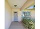 Covered front entrance featuring tiled flooring and complemented by lush landscaping at 803 Helmsman Way, Palm Harbor, FL 34685