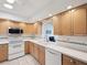 Functional kitchen featuring white appliances, light wood cabinets, and ample countertop space at 803 Helmsman Way, Palm Harbor, FL 34685