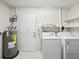 Functional laundry room featuring a washing machine, dryer, shelves, and water heater at 803 Helmsman Way, Palm Harbor, FL 34685