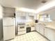 Bright kitchen featuring white appliances, ample cabinet space, and a classic tile floor at 100 Bluff View Dr # 417A, Belleair Bluffs, FL 33770
