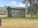 Weathered wooden livestock pen featuring a rusty metal roof surrounded by a large grassy field at 1083 Cowart Rd, Plant City, FL 33567