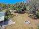 Expansive backyard featuring mature trees, a brick patio, and a charming stone fire pit at 12303 Greenland Dr, Riverview, FL 33579