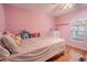 Pink bedroom with light wood floors, a window view, white shelving and lots of pillows and stuffed animals at 12303 Greenland Dr, Riverview, FL 33579
