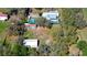 A home surrounded by lush trees, featuring a detached garage and large backyard, captured from an aerial perspective at 16349 Spring Valley Rd, Dade City, FL 33523