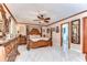 Elegant bedroom with a four-poster bed, marble floors, ceiling fan and ensuite bath at 16349 Spring Valley Rd, Dade City, FL 33523