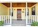 Inviting front porch with a wooden door and 'God Bless' sign, flanked by windows and black sconces at 16349 Spring Valley Rd, Dade City, FL 33523