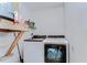 Laundry room with a washer and dryer, utility shelf, and a white wall at 16349 Spring Valley Rd, Dade City, FL 33523