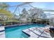 A bright, screened-in pool area featuring clear blue water, tile accents, and ample deck space for outdoor enjoyment at 16349 Spring Valley Rd, Dade City, FL 33523