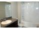 A well lit bathroom featuring a granite vanity, mirror, toilet, and shower with bathtub combo with clear curtains at 17152 Sunshine Mimosa St, Wimauma, FL 33598