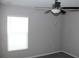 A cozy bedroom featuring gray walls, a ceiling fan, carpeted floor, and a window for natural light at 17152 Sunshine Mimosa St, Wimauma, FL 33598