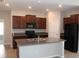 Modern kitchen with stainless appliances, granite counters, dark cabinets, and a central island at 17152 Sunshine Mimosa St, Wimauma, FL 33598
