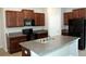 Modern kitchen with stainless steel appliances, dark cabinetry, granite countertops, and central island at 17152 Sunshine Mimosa St, Wimauma, FL 33598