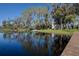 Scenic lake view with a small dock, boat, and the charming home nestled among the trees on the shore at 18715 Lakeshore Dr, Lutz, FL 33549