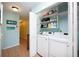 Bright laundry room with front loading washer and dryer, storage shelves, and tile floors at 19937 Gulf Blvd # B-3, Indian Shores, FL 33785