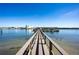 Scenic view of a wooden pier extending into the bay with clear water and buildings in the distance at 19937 Gulf Blvd # B-3, Indian Shores, FL 33785