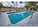 Inviting in-ground pool surrounded by grey stone, landscaping, and a white picket fence overlooking a waterway at 22516 Bolanos Ct, Port Charlotte, FL 33952