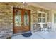 Entryway with decorative wood doors, stone wall, and white rocking chairs at 2660 Powell Ln, Tarpon Springs, FL 34688