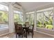 Bright sunroom with large windows overlooking lush backyard and a round wooden table at 2660 Powell Ln, Tarpon Springs, FL 34688
