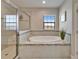 Bright bathroom featuring a large tub, glass shower, and tiled walls at 2911 Silva Wood Dr, Valrico, FL 33596