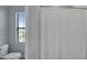 Bright bathroom featuring a toilet, window with blinds, and a white shower curtain at 2911 Silva Wood Dr, Valrico, FL 33596