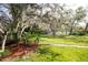 A serene backyard is adorned with mulch beds and mature trees, offering a tranquil retreat at 3212 Kilmer Dr, Plant City, FL 33566