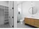 Modern bathroom featuring a wood vanity, round mirror, glass shower, and black and white patterned tile flooring at 48 Sandpiper Rd, Tampa, FL 33609