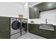 Well-equipped laundry room featuring front-load washer and dryer, farmhouse sink, and modern cabinetry at 48 Sandpiper Rd, Tampa, FL 33609